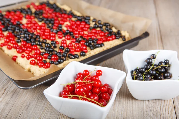 Rote und schwarze Johannisbeeren mit selbst gebackenem Kuchen auf dem Hintergrund — Stockfoto