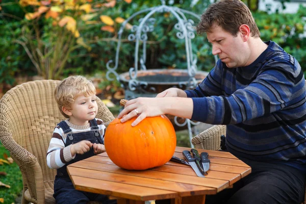 Jonge man en peuter jongen halloween pompoen maken — Stockfoto