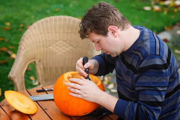 Young man making halloween pumpkin — Stock Photo, Image