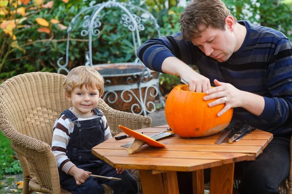 Hombre joven y niño pequeño haciendo calabaza de halloween — Foto de Stock