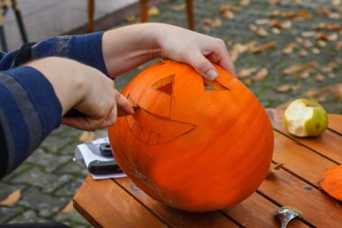 Cadılar bayramı fenerini hazırlamak için balkabağını oyuyor.