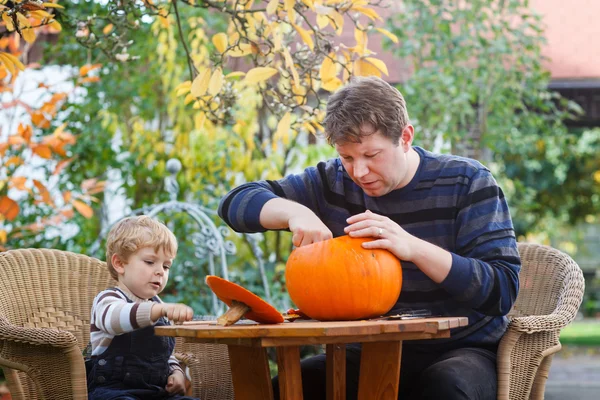 Hombre joven y niño pequeño haciendo calabaza de halloween —  Fotos de Stock