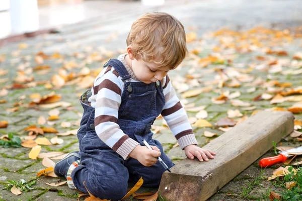 Маленький мальчик играет в осеннем саду — стоковое фото