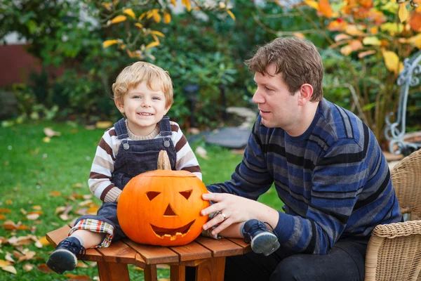 Hombre joven y niño pequeño haciendo calabaza de halloween —  Fotos de Stock