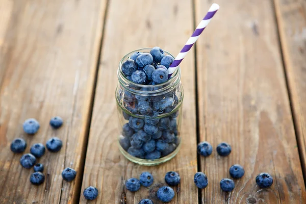 Ripe blueberries in glass jar on a wooden table — Stock Photo, Image