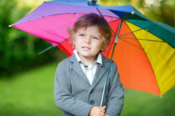 Little cute toddler boy with colorful umbrella and boots, outdoo — Stock Photo, Image