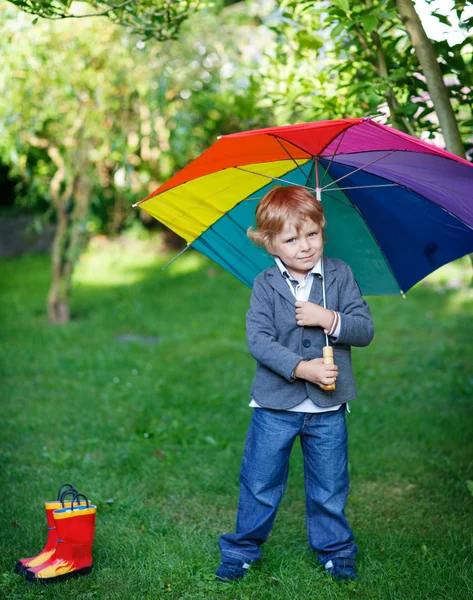 Malé roztomilé batole chlapce s barevný deštník a boty, outdoo — Stock fotografie