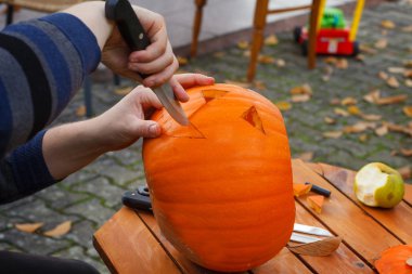 Cadılar bayramı fenerini hazırlamak için balkabağını oyuyor.