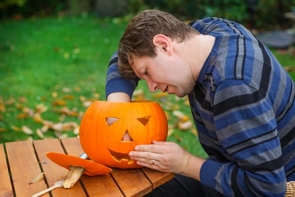 Junger Mann bastelt Halloween-Kürbis — Stockfoto