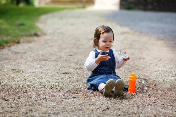Маленька мила дівчинка грає з мильними бульбашками в літньому парку — стокове фото