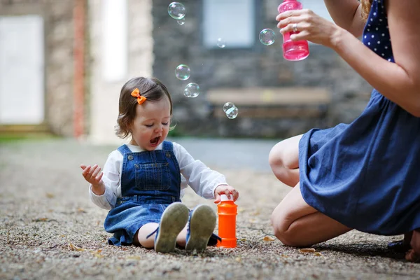Pouco bonito bebê menina brincando com bolhas de sabão no parque de verão — Fotografia de Stock