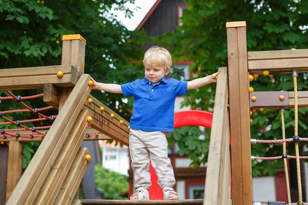 Petit garçon tout-petit assis sur l'aire de jeux — Photo