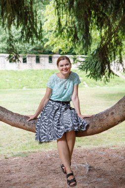 ağaç üzerinde oturan ve rahatlatıcı genç kadın