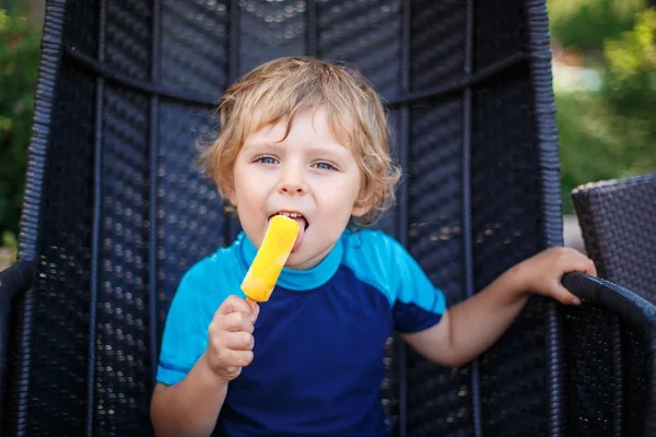 Piccolo ragazzo biondo che mangia gelato giallo — Foto Stock