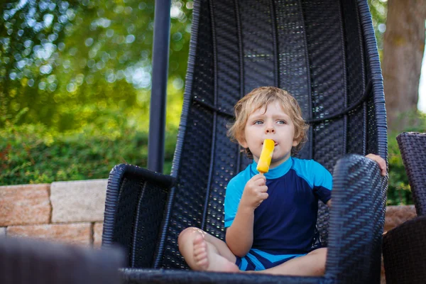 Pequeño chico rubio comiendo helado amarillo —  Fotos de Stock