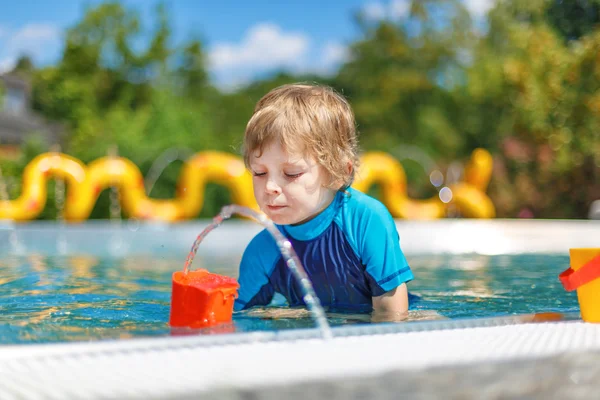 Criança bonito brincando com água na piscina exterior — Fotografia de Stock