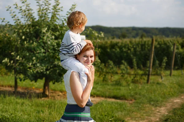 Young mother giving little boy a ride on shoulders on countrysid — Stock Photo, Image