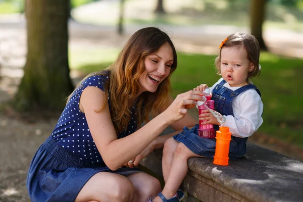 Piękna mama i córeczka dmuchanie baniek mydlanych w sumie — Zdjęcie stockowe