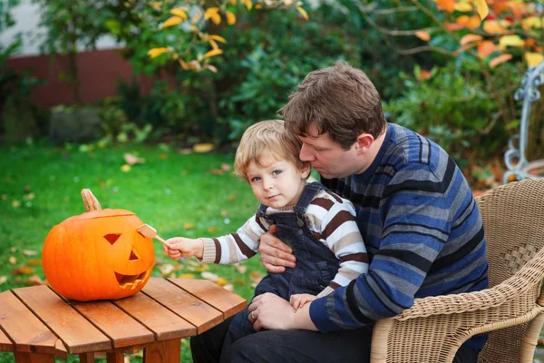 Jonge man en peuter jongen halloween pompoen maken — Stockfoto