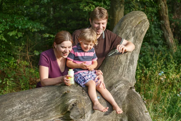 Família de três bolhas de sabão soprando juntos na floresta de verão — Fotografia de Stock