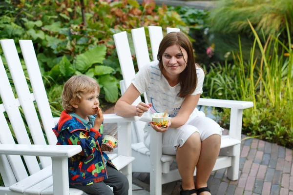 Mujer joven y niño pequeño comiendo helado al aire libre — Foto de Stock