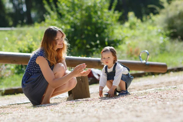 Beautiful mother and little daughter on playground — Stock Photo, Image