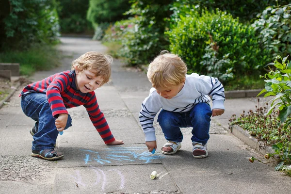 Twee kleine broer of zus jongens schilderen met krijt buitenshuis — Stockfoto