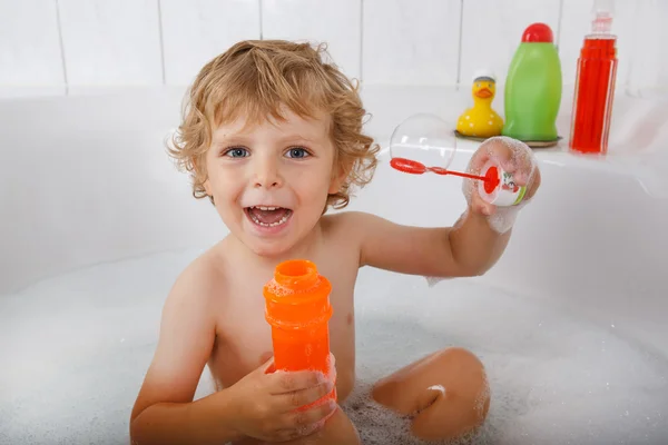 Adorable blond toddler boy playing with soap bubbles in bathtub — Stock Photo, Image