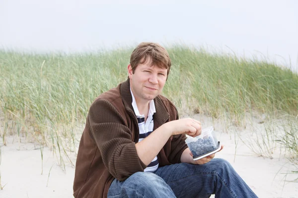 Jeune homme heureux se détendre sur les dunes de sable de la plage de Saint-Pierre — Photo