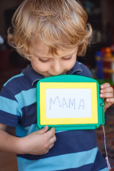 Маленький малюк з дошкою для малювання пише своє перше слово — стокове фото
