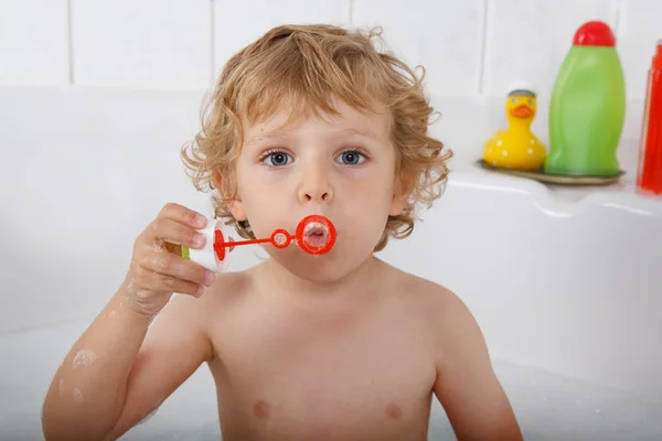 Aranyos szőke totyogó fiú játszik a fürdőkádban szappanbuborékok — Stock Fotó