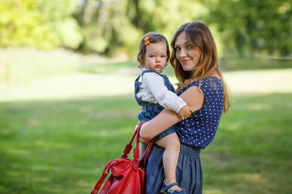 Schöne Mutter und kleine Tochter spazieren im Sommerpark — Stockfoto