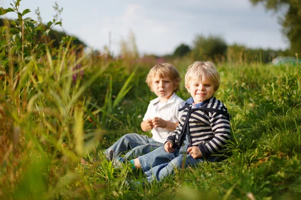 Two little brother boys playing near forest lake on summer eveni — Stock Photo, Image