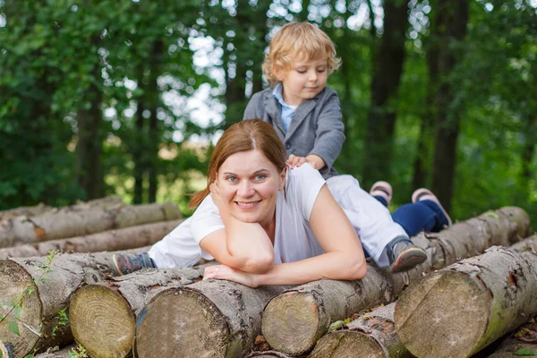 Jovem mãe e pequeno filho se divertindo na floresta de verão . — Fotografia de Stock