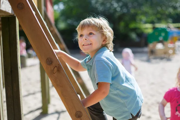 Malý kluk baví na hřiště, město na slunečný den — Stock fotografie