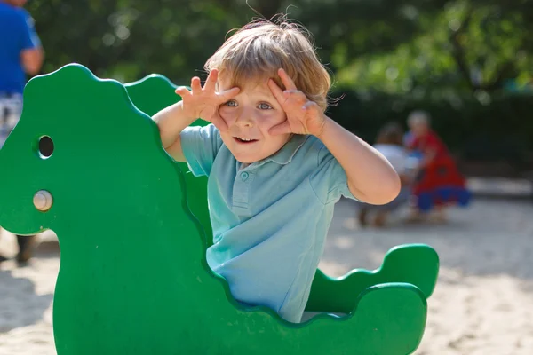 Menino se divertindo no playground da cidade no dia ensolarado — Fotografia de Stock