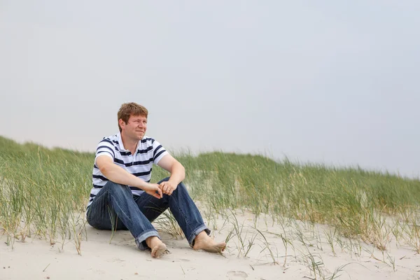 Young happy man relaxing on sand dunes of the beach of St.Peter — Stock Photo, Image
