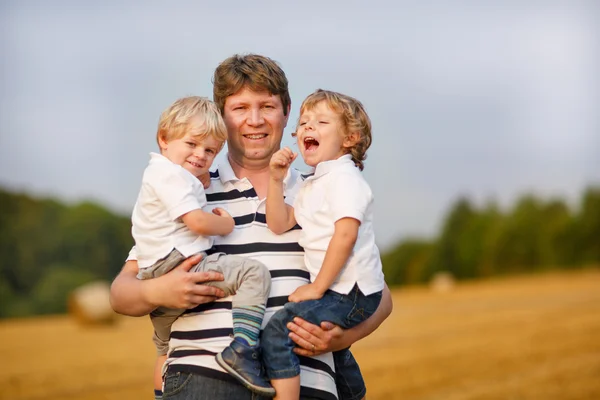 Young father and two little brother boys having fun on yellow ha — Stock Photo, Image