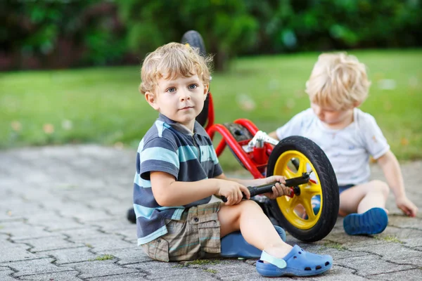 두 명의 작은 소년, 형제 자매, 자전거 야외 수리. — 스톡 사진