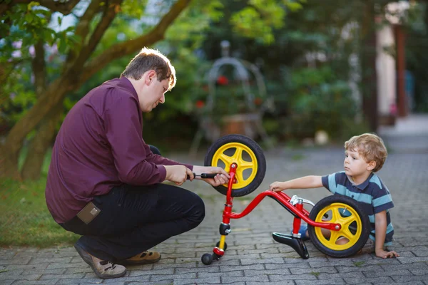 Bambino e suo padre riparano la ruota della bicicletta all'aperto . — Foto Stock