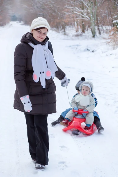 Två små syskon och deras mamma att ha kul på släde — Stockfoto