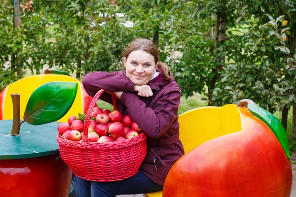 Bir meyve bahçesinde Kırmızı elma yiyen genç kadın — Stok fotoğraf