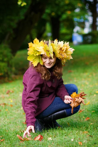 Jovem feliz com bordo de outono deixa guirlanda no parque . — Fotografia de Stock