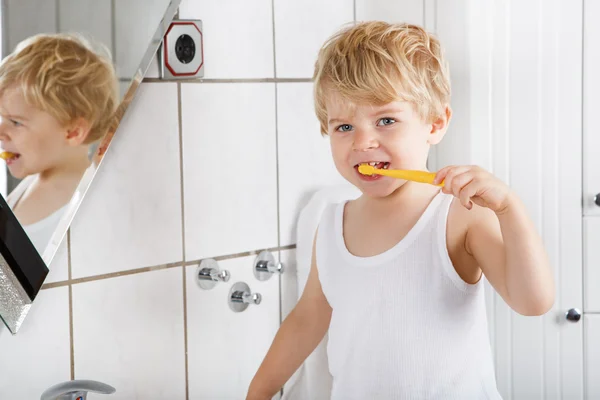Lindo niño con ojos azules y cabello rubio cepillándose los dientes — Foto de Stock