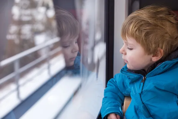 Schattige kleine jongen kijkt uit raam van de trein — Stockfoto