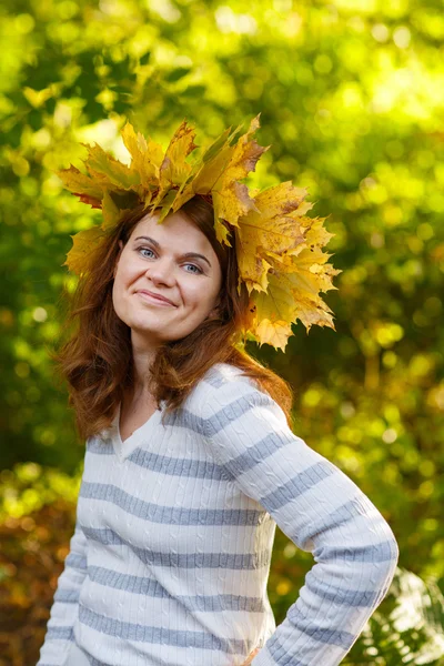 Happy young woman with autumn maple leaves garland in park. — Stock Photo, Image