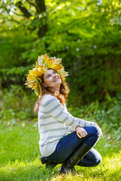 Mujer joven feliz con otoño de arce deja guirnalda en el parque . — Foto de Stock