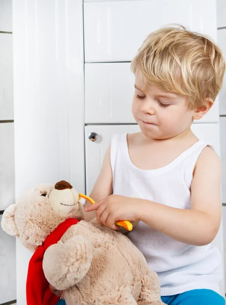 Little boy playing with teddy bear toy and brushing teeth. — Stock Photo, Image