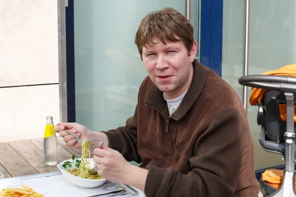Jeune homme manger des pâtes dans un restaurant en plein air . — Photo