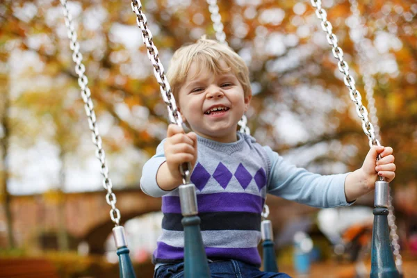 Little cute boy having fun on chain swings — Stock Photo, Image